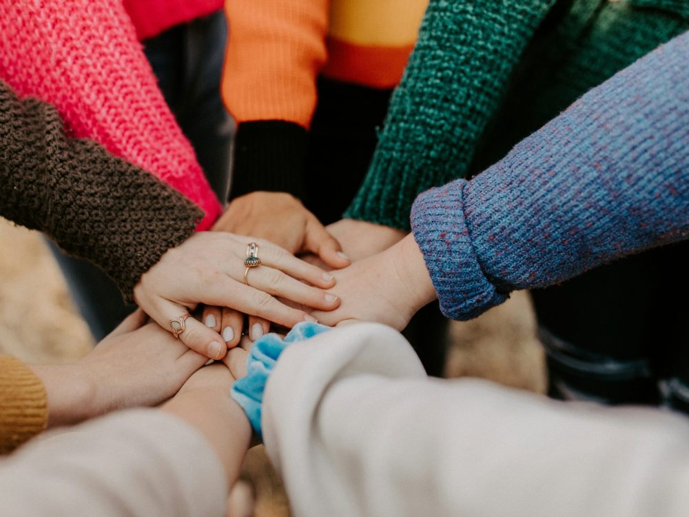 women putting hands together in a circle