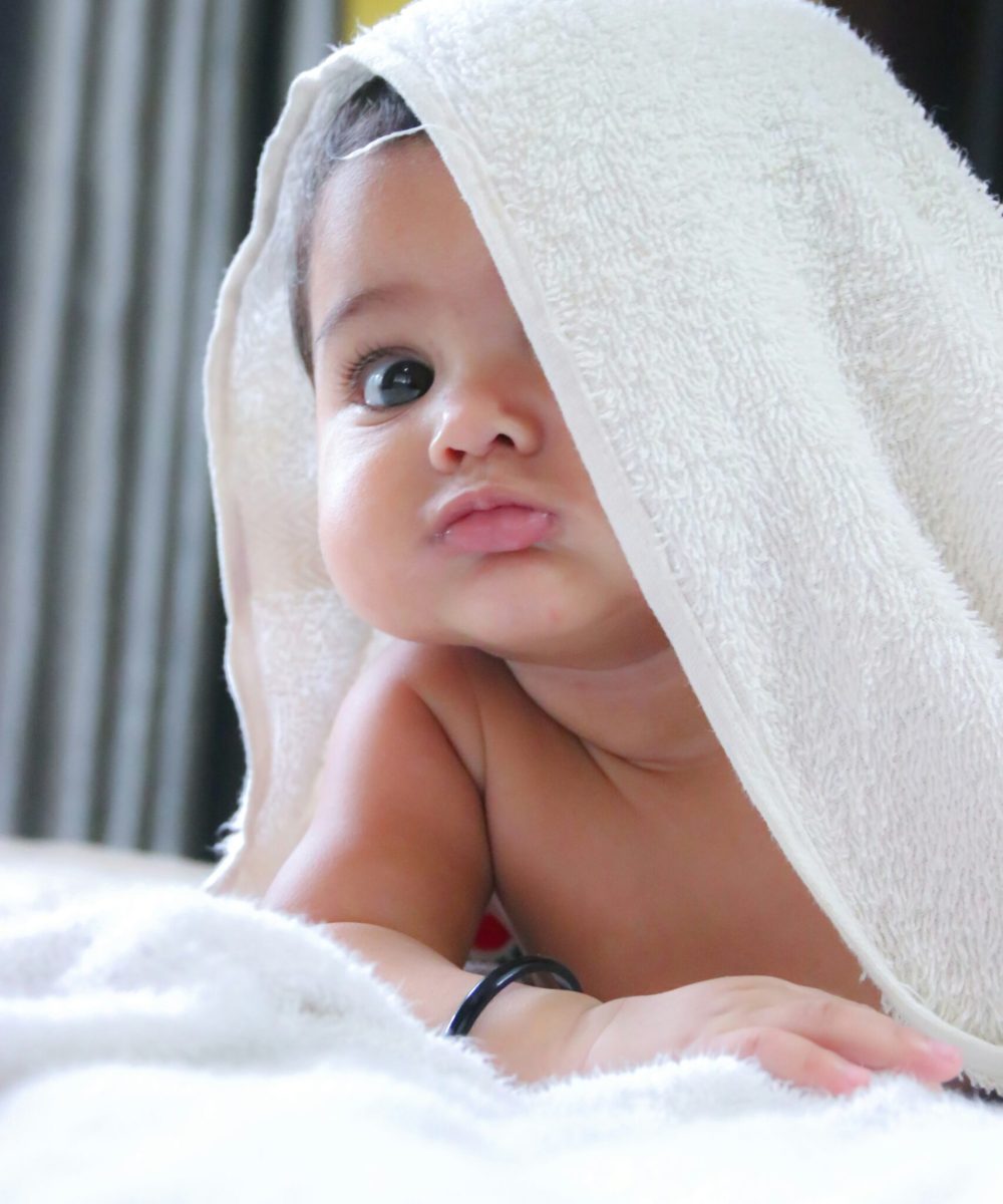 baby looks up from beneath blanket
