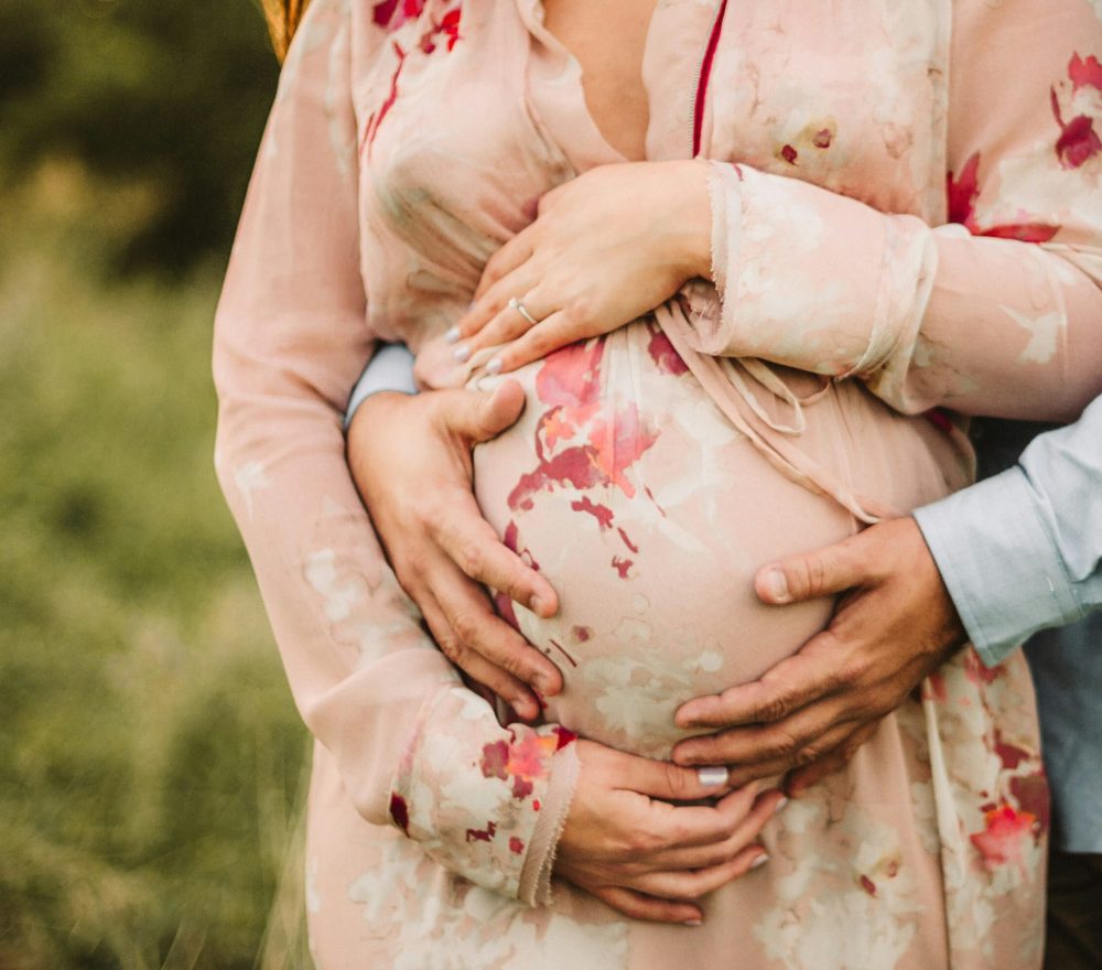 pregnant woman hugged by partner in nature